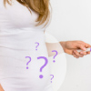Female holding a pregnancy test with question marks around her belly, depicting female infertility