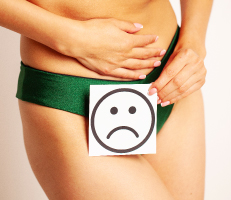 Female with her hand on her abdomen and a sad smiley face card on her underwear