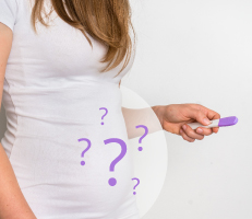 Female holding a pregnancy test with question marks around her belly, depicting female infertility